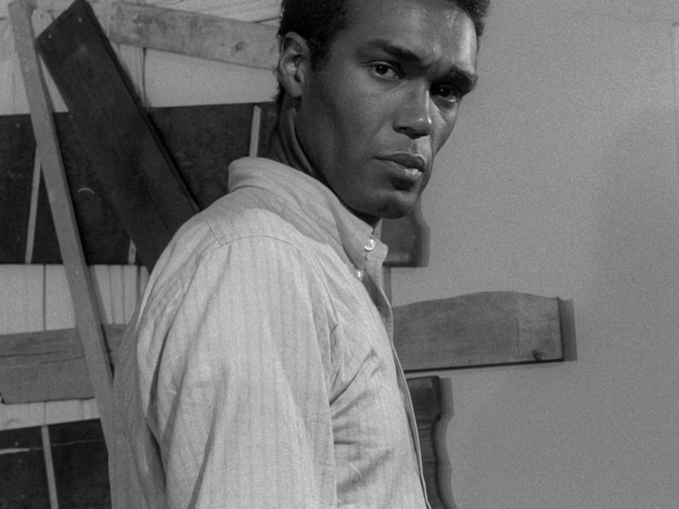 Duane Jones in front of a boarded-up door in Night of the Living Dead.