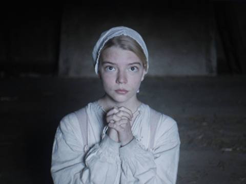 Anya Taylor Joy wearing early American settler clothes, kneeling with her hands folded to pray in The Witch