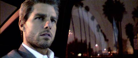 Tom Cruise as Vincent from Collateral in the back of a car with palm trees out the window 