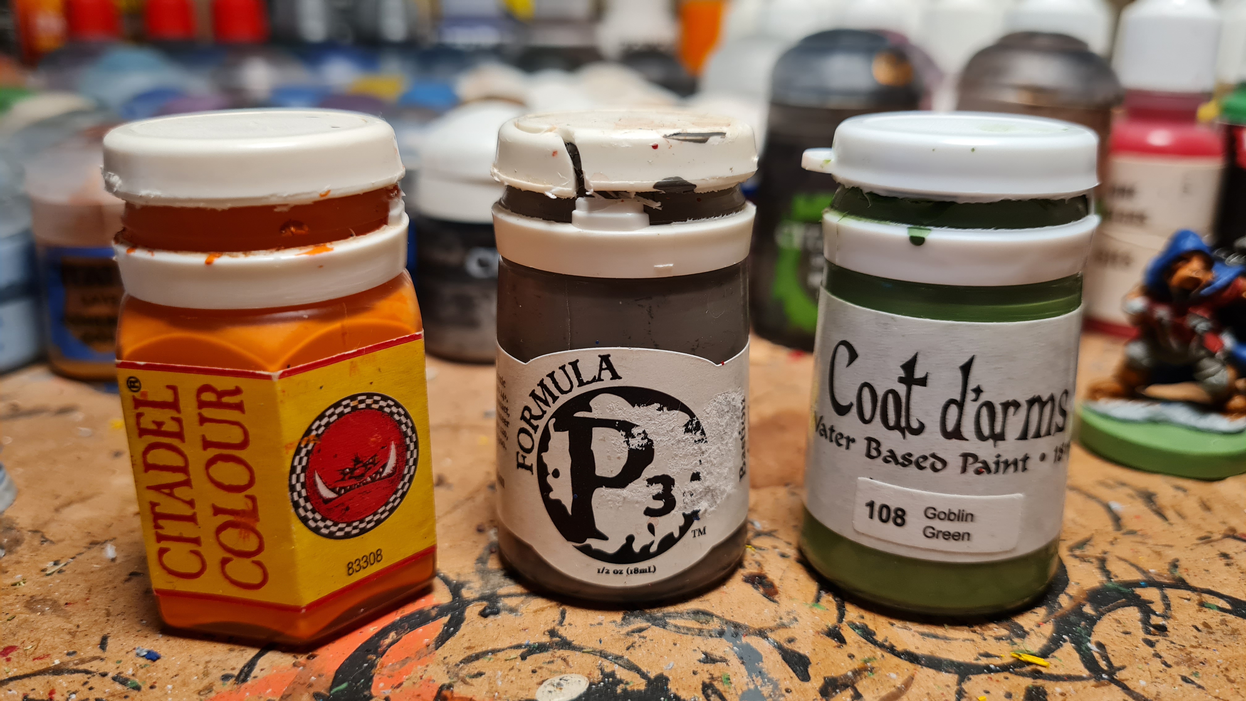 Left to right: Paints from Games Workshop's 1994 Citadel Colour, Privateer Press's Formula P3, and Coat d'Arms paint. All three lines are or were manufactured by U.K.-based HMG Paints, and have their signature stout pots with white plastic lids.