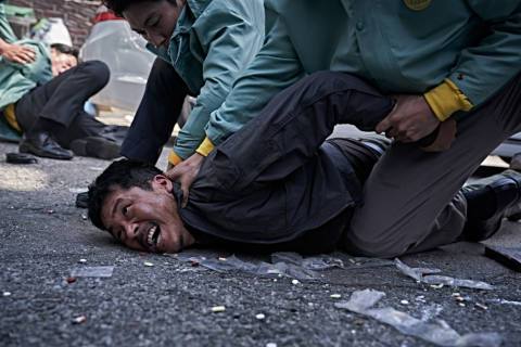 Jin Kyunghun (Yang Ik-june) getting arrested and pinned to the ground in a still from Hellbound season 