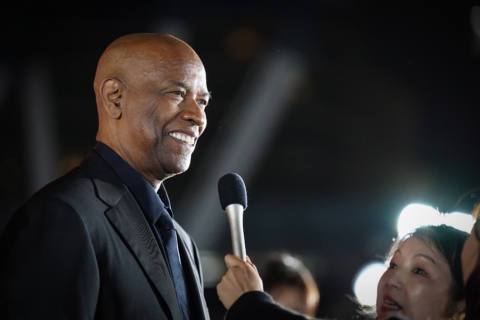 Denzel Washington smiles with a microphone in his face