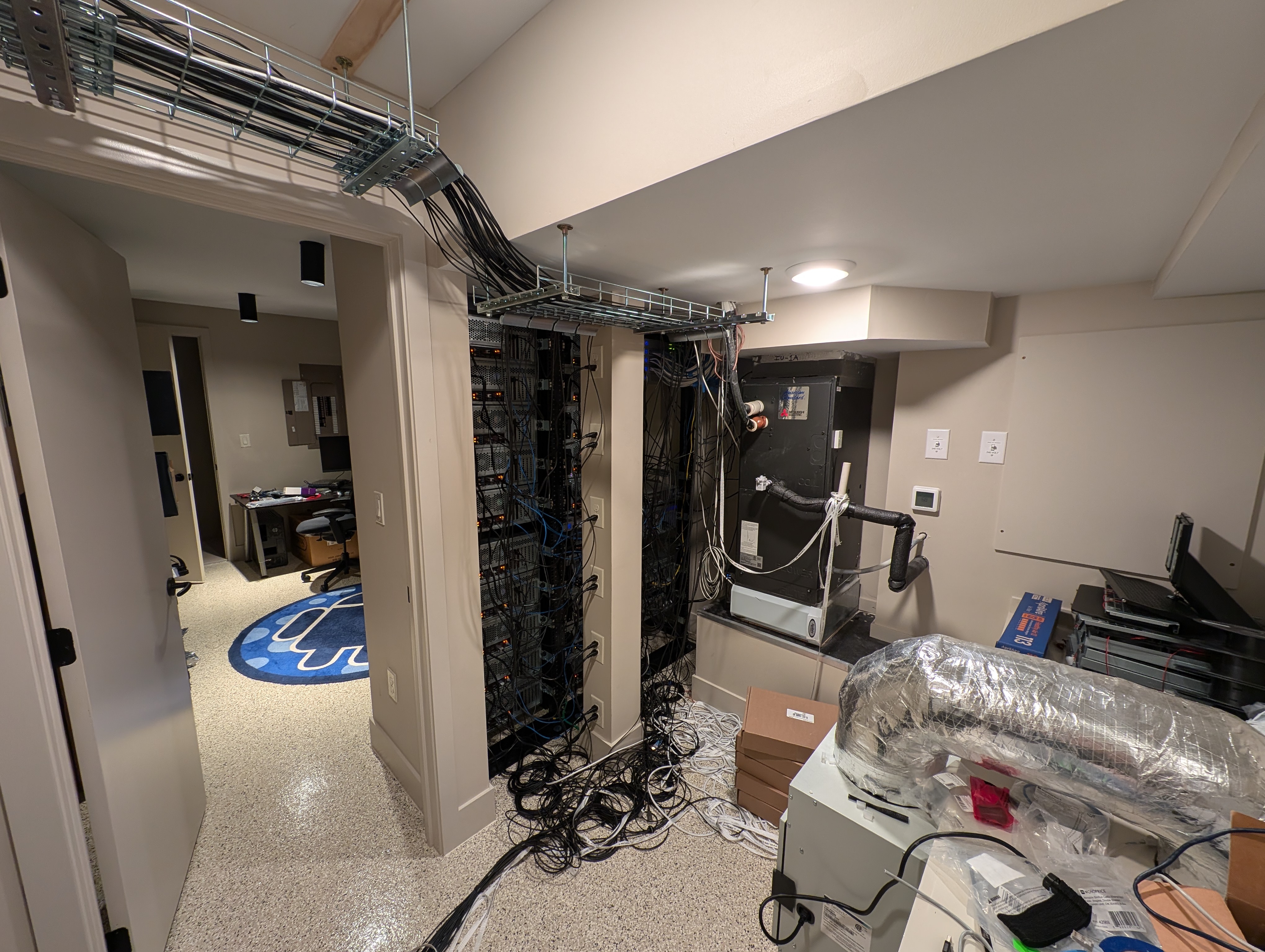 The 'hot side' of the LAN party house's server room. Wires and fans can be seen all around--this space is definitely not intended for guests to regularly access.