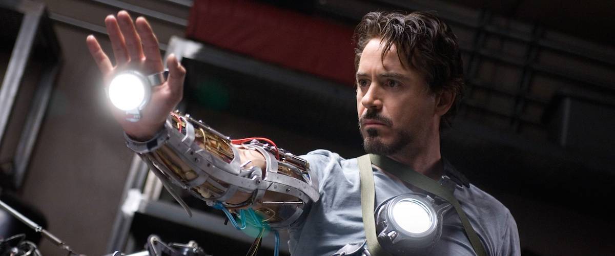 Robert Downey Jr. holds out his hand wearing an Iron Man arm in Iron Man