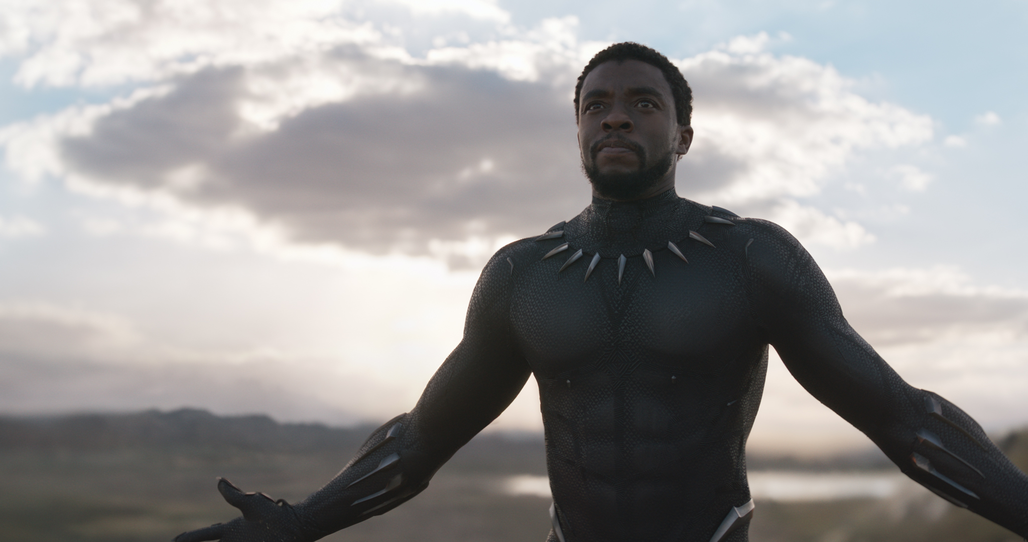 Chadwick Boseman holds out his arms in the Black Panther suit in Black Panther.