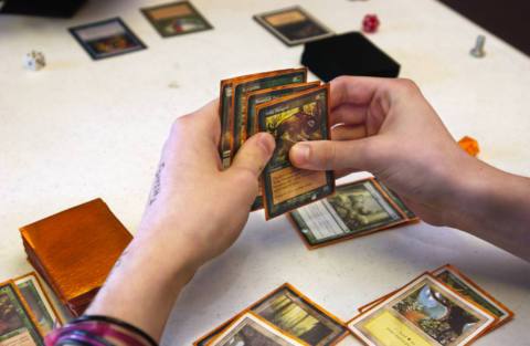 A close-up photo of a person’s hand holding Magic: The Gathering cards at Crossroad Games in Standish.