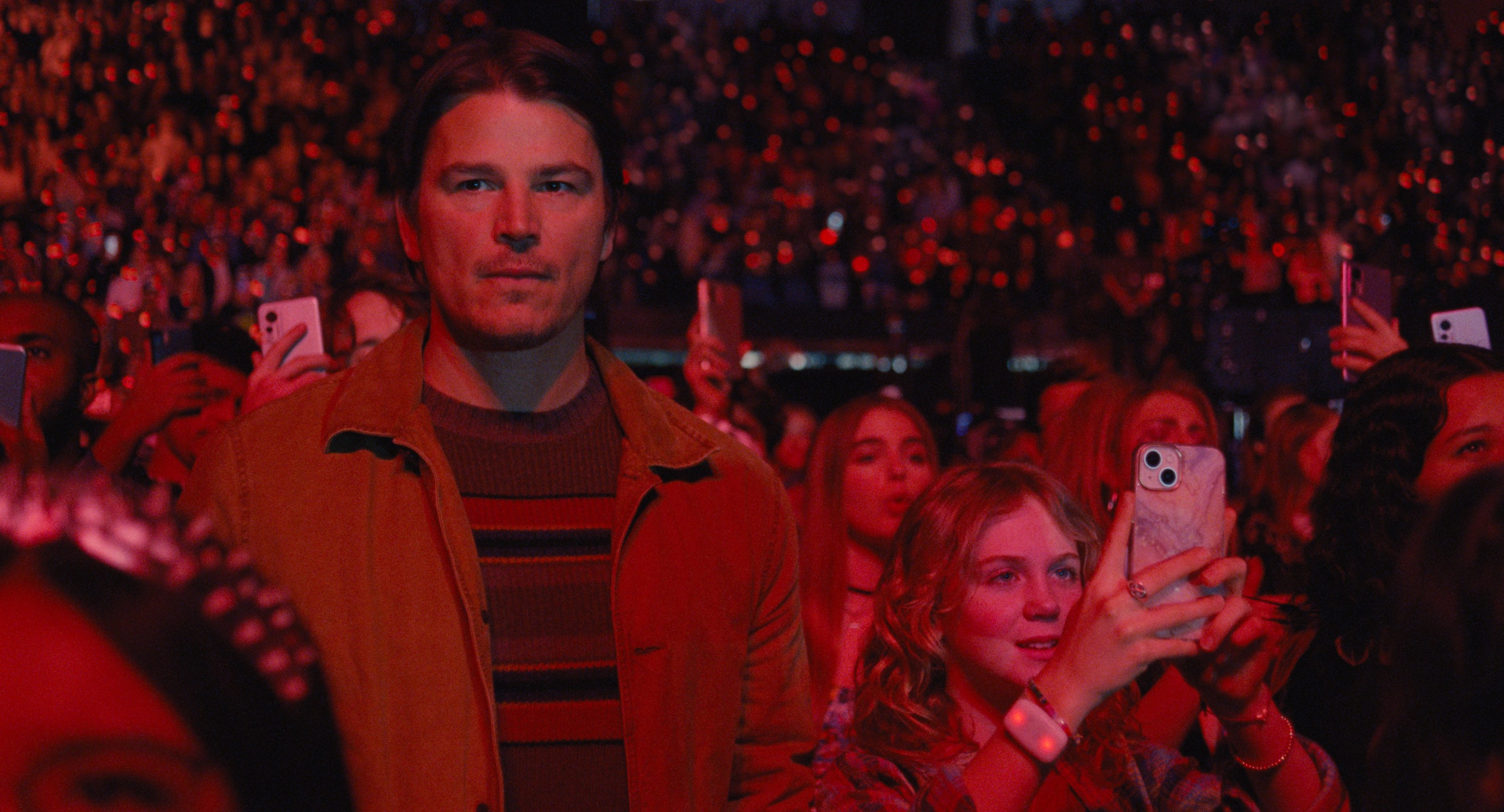 Serial killer Cooper (Josh Hartnett) looks pensive as he stands under dim red lights in a huge crowd at a concert in M. Night Shyamalan’s Trap Serial killer Cooper (Josh Hartnett) looks pensive as he stands under dim red lights in a huge crowd at a concert in M. Night Shyamalan’s Trap