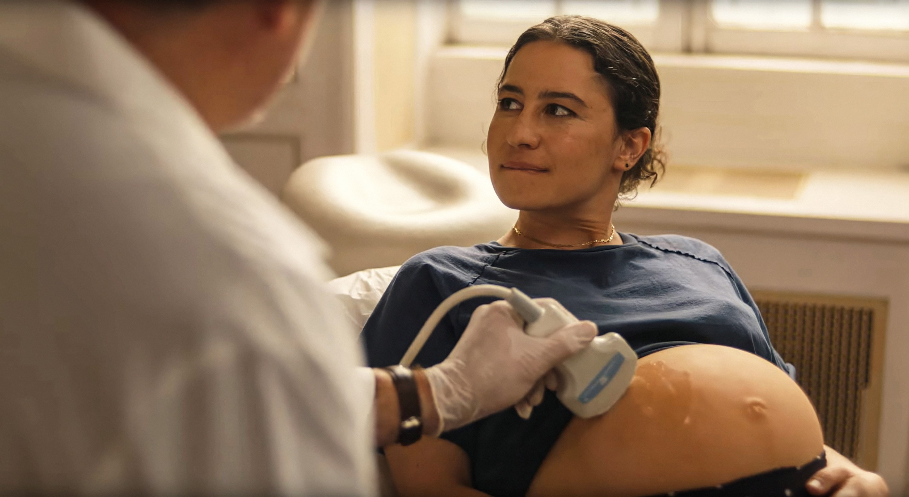 Ilana Glazer as Eden, a pregnant woman sitting and getting an ultrasound