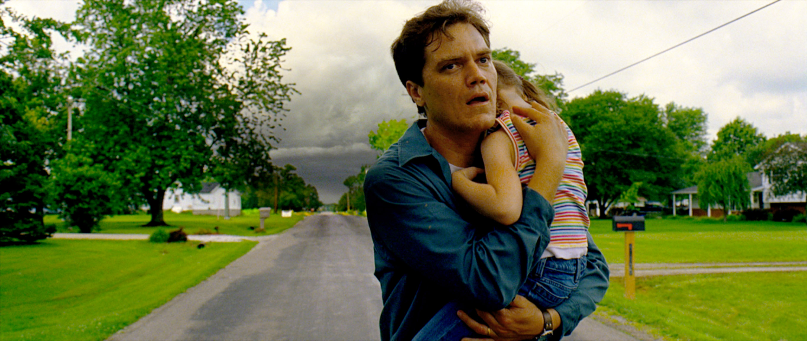 Michael Shannon running down a quiet road and holding a child in his arms in Take Shelter 