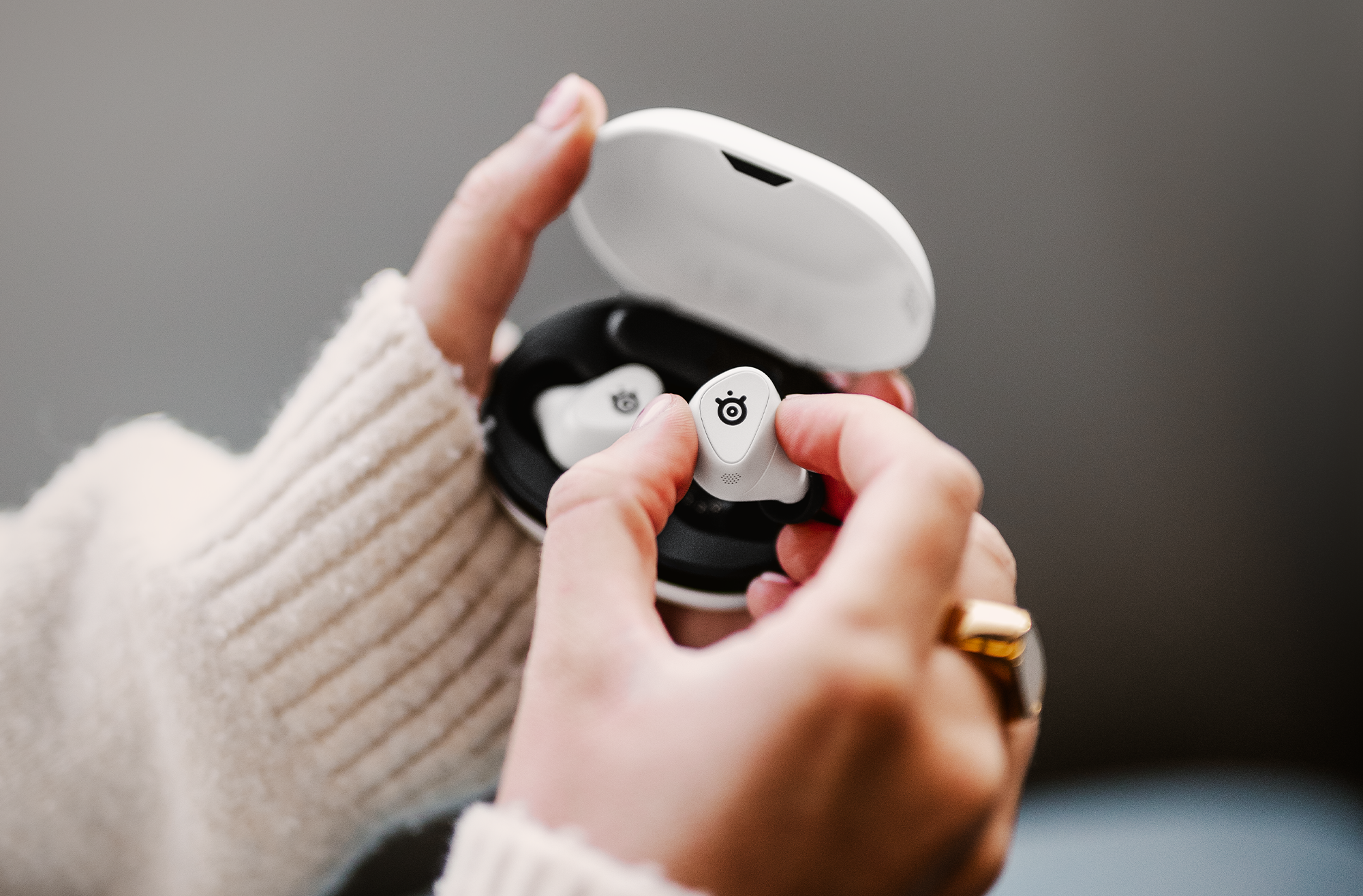 A stock photo of the white Steelseries Arctis Gamebuds being removed from their case