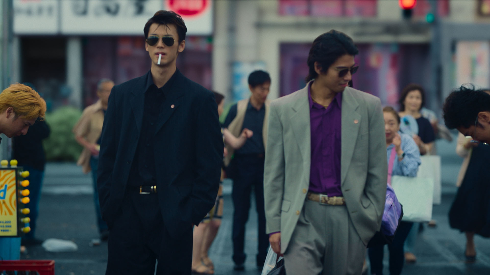 Kiryu (Ryoma Takeuchi) walking with his friend and looking cool with shades and a cigarette in a still from Like a Dragon: Yakuza