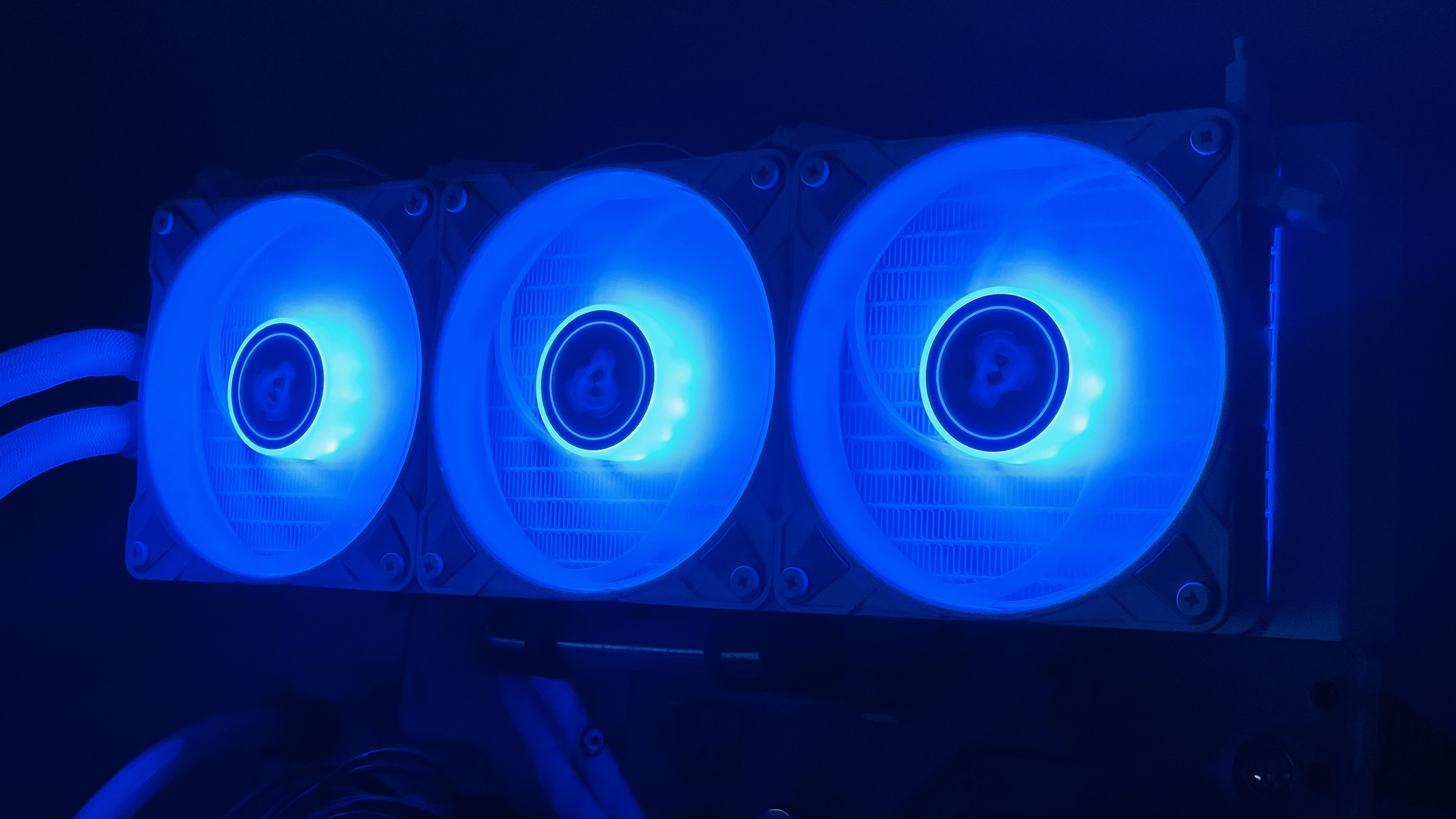 An array of three cooling fans, all glowing blue to demonstrate the fans' RGB lighting feature.