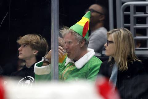 A photo of 2024 era Will Ferrell in his Elf costume at a hockey game, drinking a beer