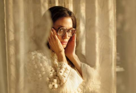 Angelina Jolie looks at the camera through large glasses