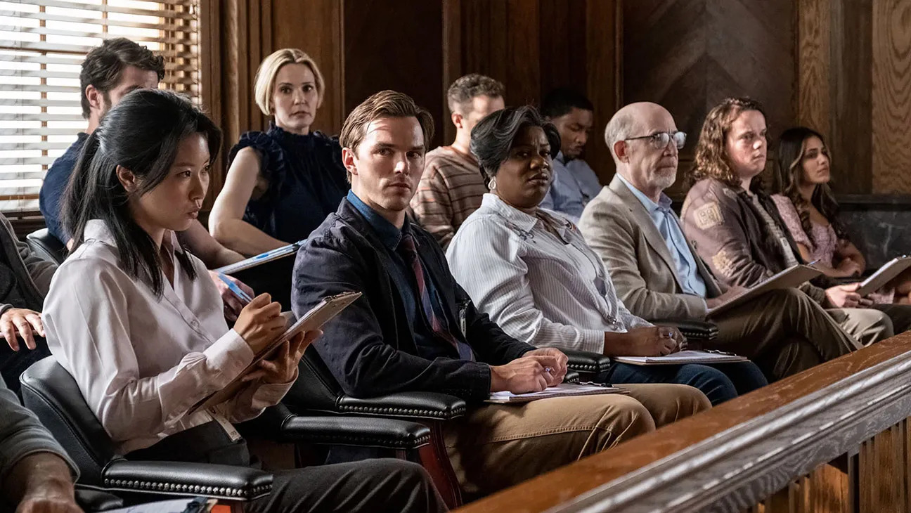 A man (Nicholas Hoult) seated in a jury box sext to several other people taking notes in Juror #2 A man (Nicholas Hoult) seated in a jury box sext to several other people taking notes in Juror #2