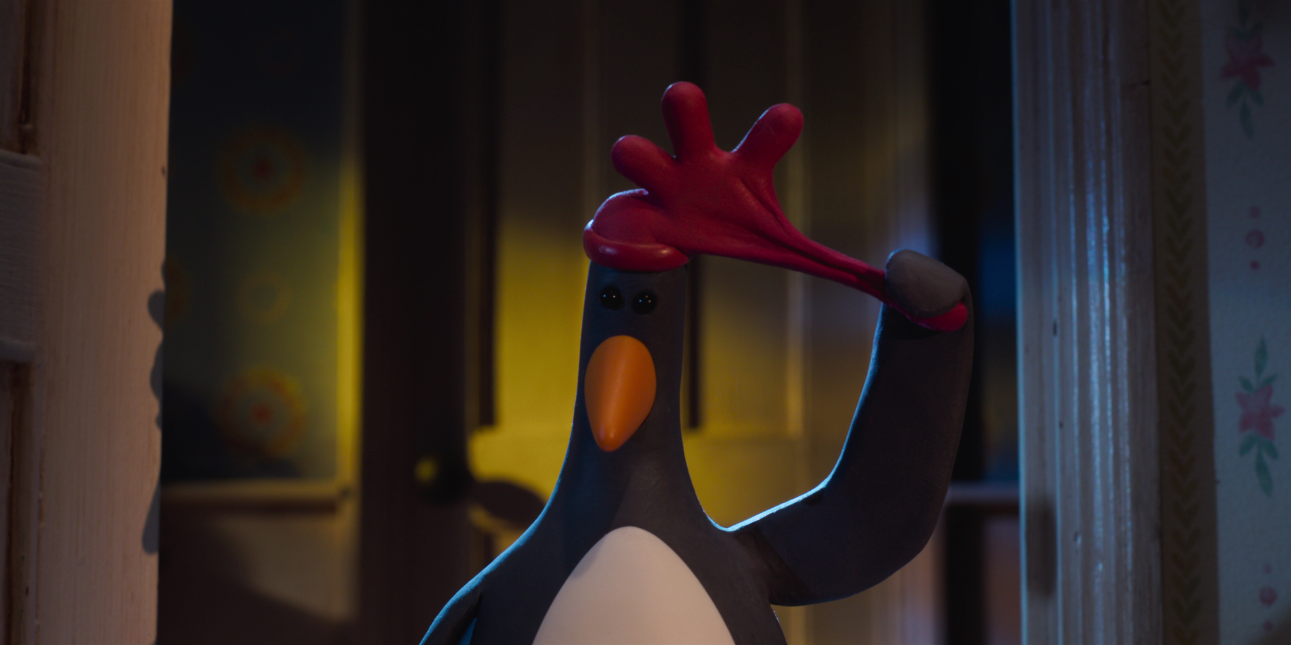 Feathers McGraw, a claymation penguin, pulling off a red rubber glove hat that looks like a rooster’s comb in Wallace & Gromit: Vengeance Most Fowl