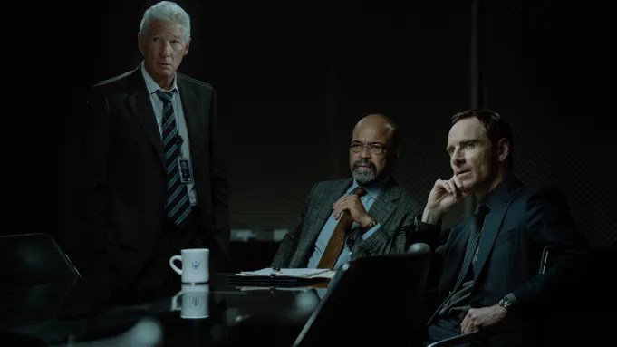 Three men in a still from The Agency season 1 sitting at a table looking stunned Three men in a still from The Agency season 1 sitting at a table looking stunned