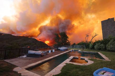 TOPSHOT – A brush fire burns near homes in Pacific Palisades, California on January 7, 2025. A fast-moving brushfire in a Los Angeles suburb burned buildings and sparked evacuations Tuesday as “life threatening” winds whipped the region. More than 200 acres (80 hectares) was burning in Pacific Palisades, a upscale spot with multi-million dollar homes in the Santa Monica Mountains, shuttering a key highway and blanketing the area with thick smoke. (Photo by David Swanson / AFP) (Photo by DAVID SWANSON/AFP via Getty Images)