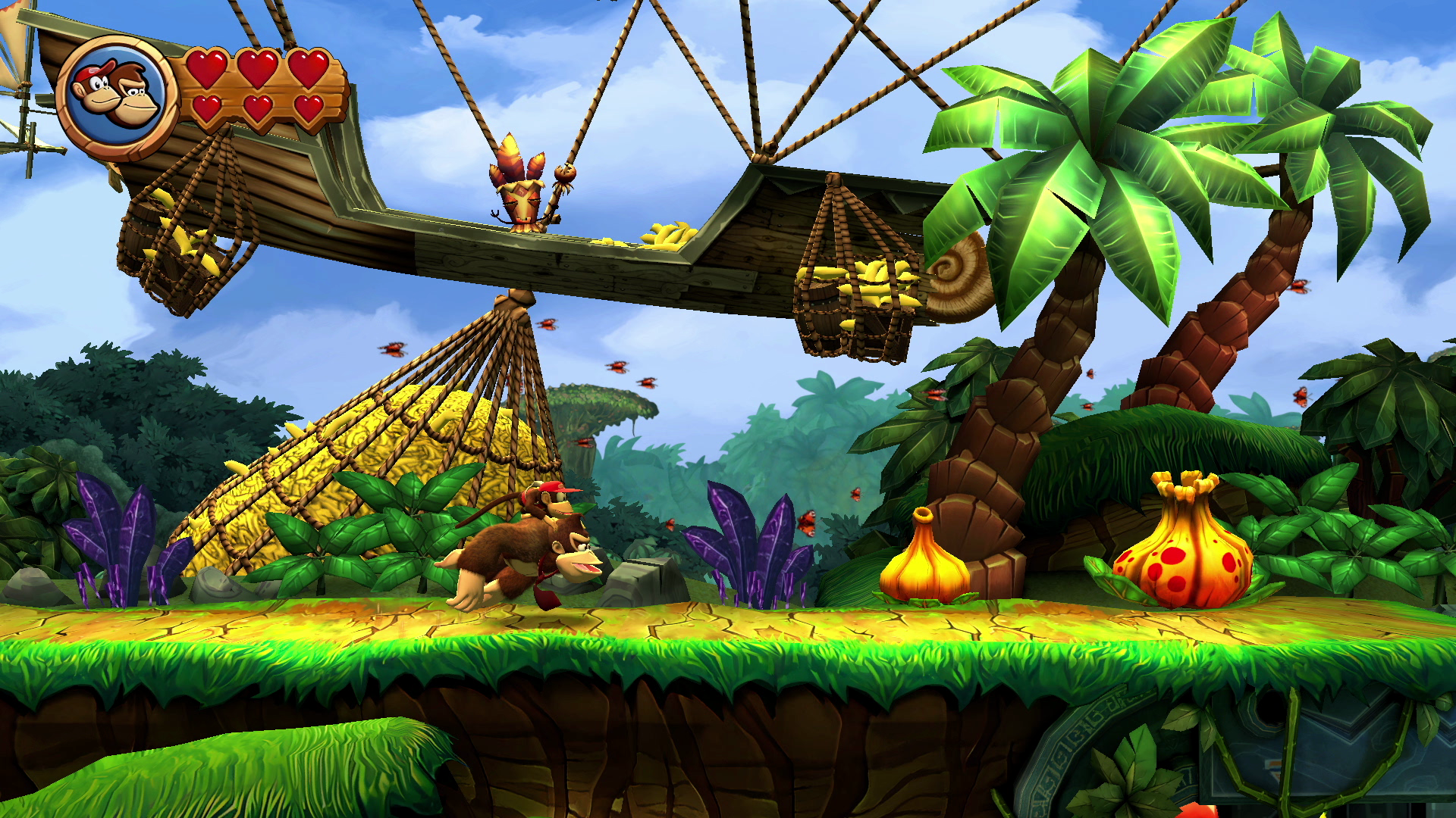 A screenshot of Donkey Kong carrying Diddy Kong on his back through a jungle with a floating barge holding a net filled with bananas in Donkey Kong Country Returns HD. A screenshot of Donkey Kong carrying Diddy Kong on his back through a jungle with a floating barge holding a net filled with bananas in Donkey Kong Country Returns HD.