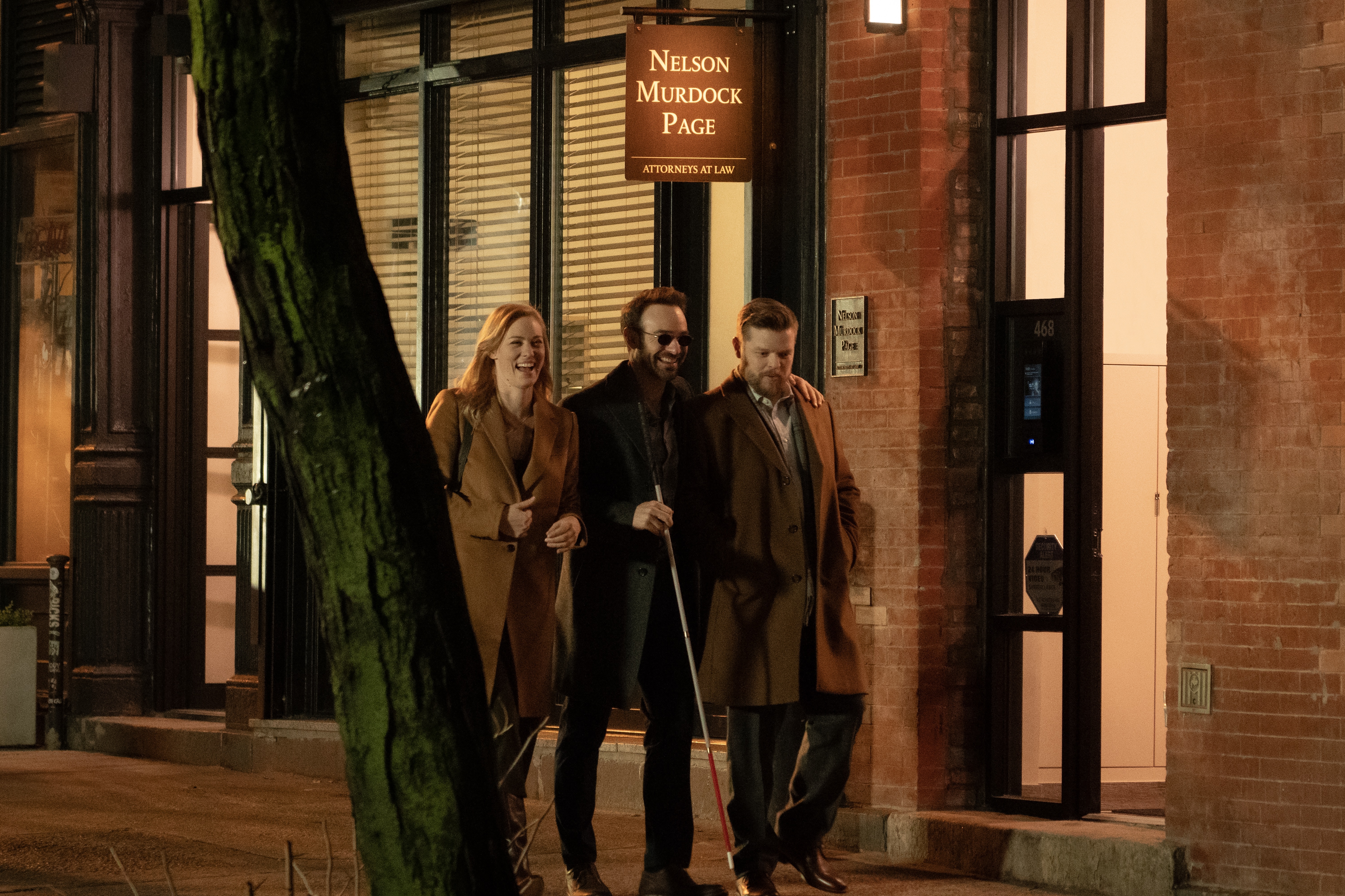 Charlie Cox, Deborah Ann Woll, and Elden Hanson walk on the street outside the Nelson, Murdock, Page office in Daredevil: Born Again