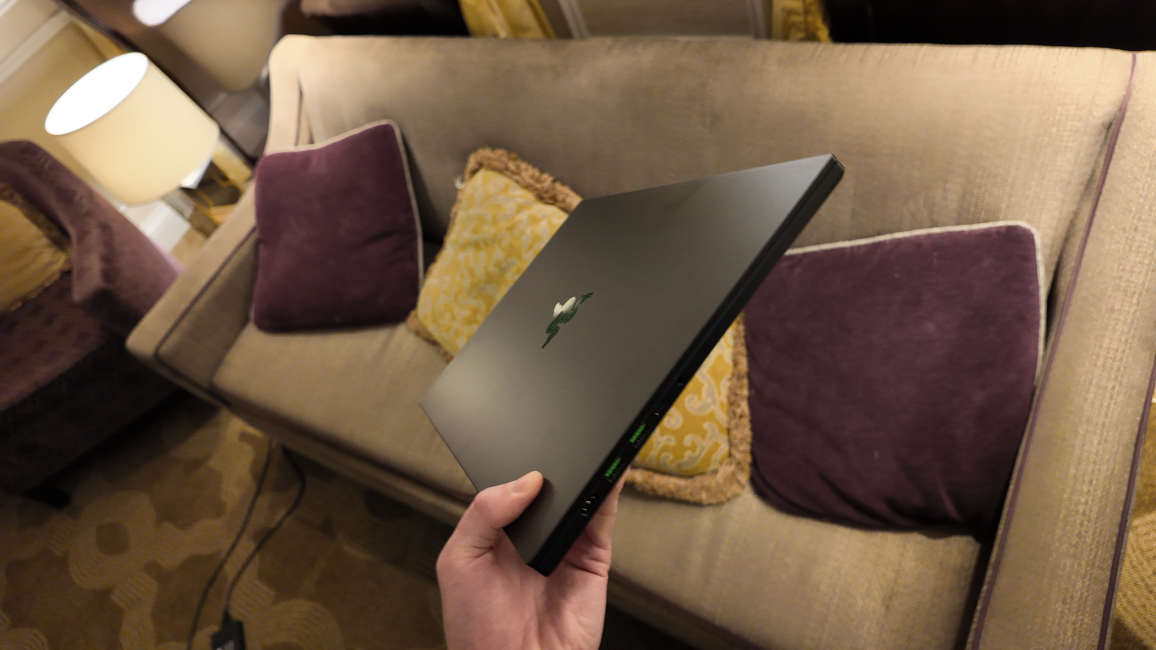 The new Razer Blade 16 being held at an angle by one hand, to show its new, sleeker form factor.