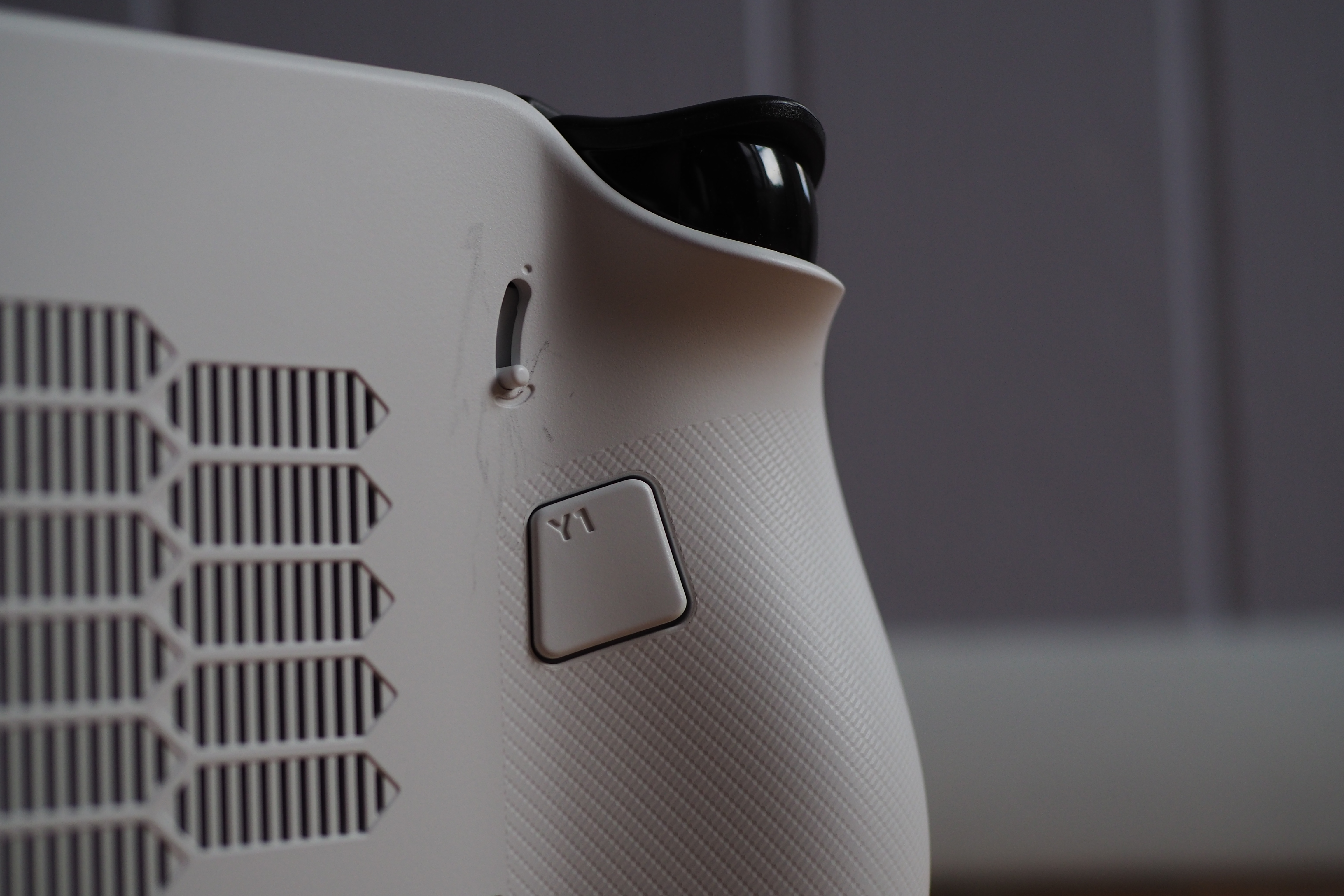 A photograph of the back side of the Lenovo Legion Go S, highlighting its rear customizable back button, as well as its analog sensitivity switch. A photograph of the back side of the Lenovo Legion Go S, highlighting its rear customizable back button, as well as its analog sensitivity switch.