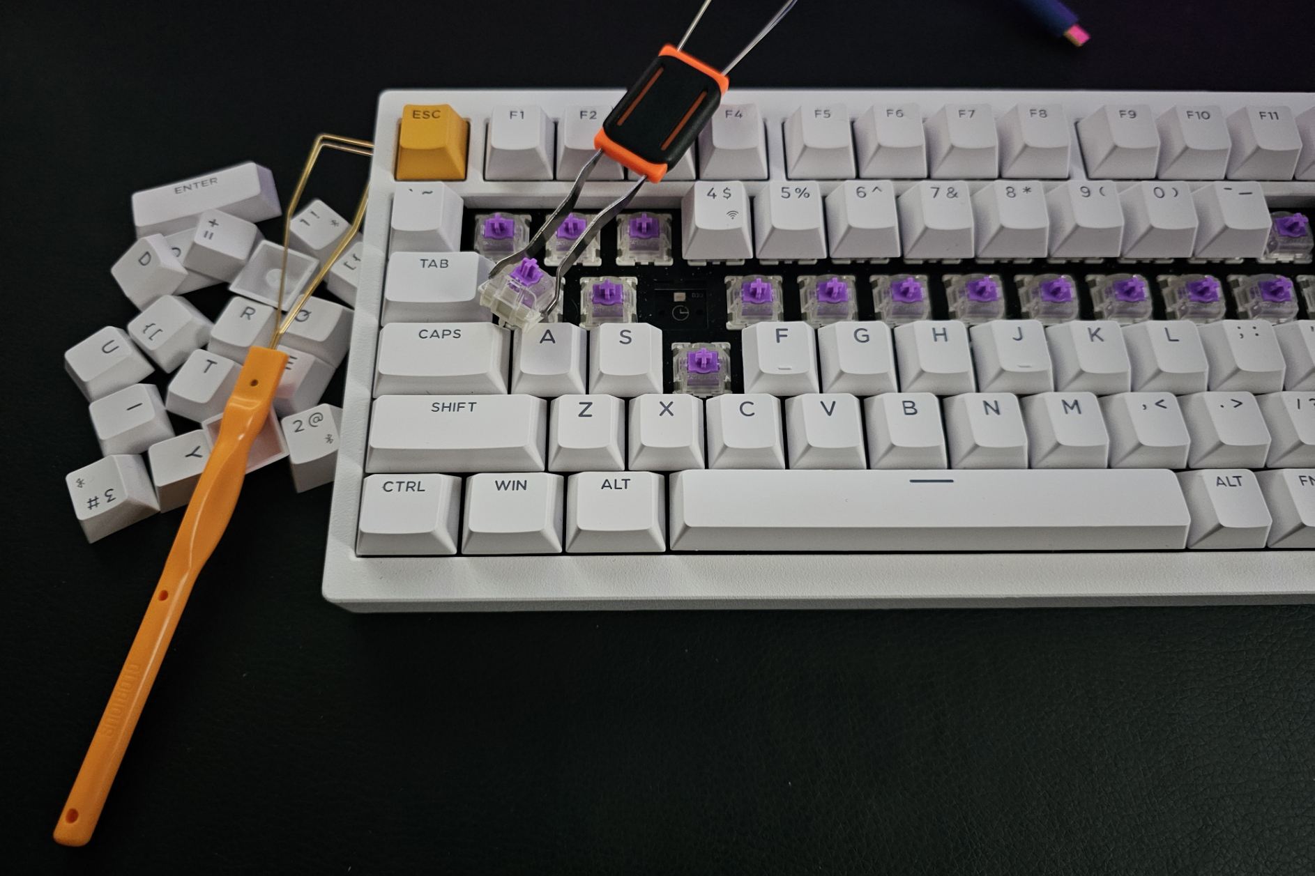 A photo of the Lemokey P1 HE partly disassembled with some keycaps and a switch removed with a keycap and switch puller in frame. A photo of the Lemokey P1 HE partly disassembled with some keycaps and a switch removed with a keycap and switch puller in frame.