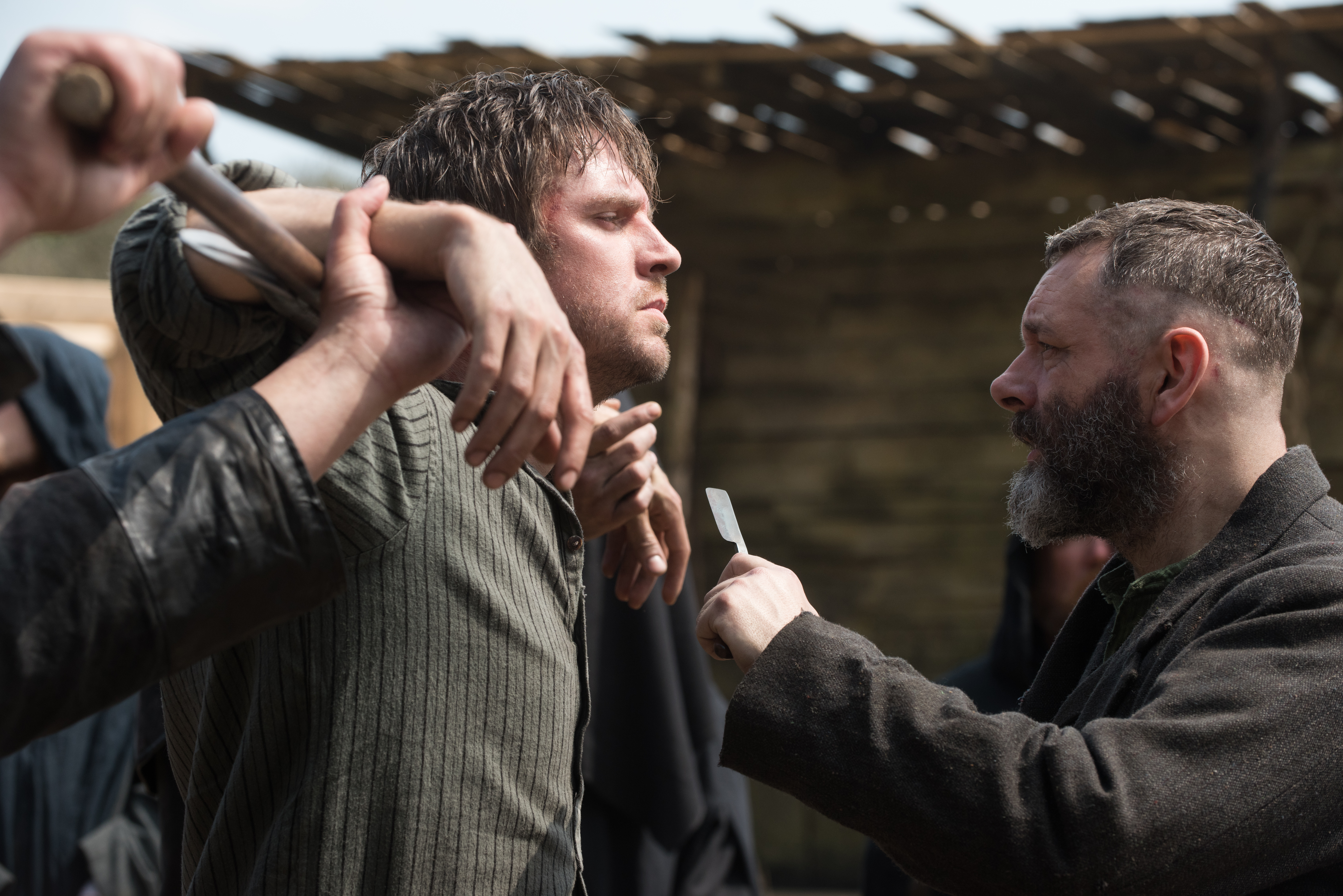 Dan Stevens is held up by his arms as Michael Sheen holds a blade towards his knife in Apostle Dan Stevens is held up by his arms as Michael Sheen holds a blade towards his knife in Apostle