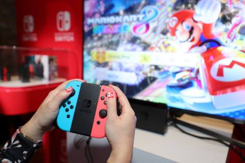 A photo of the Nintendo Switch preview event depicting a person holding the Joy-Con controllers and playing Mario Kart 8 Deluxe