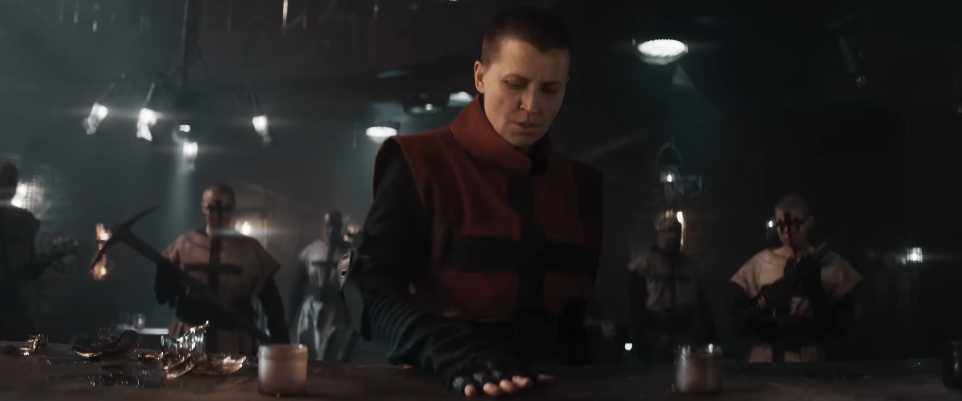 The leader of the Christian cult in In the Lost Lands puts her hand down on the bar in an underlit tavern, as her soldiers stand behind her