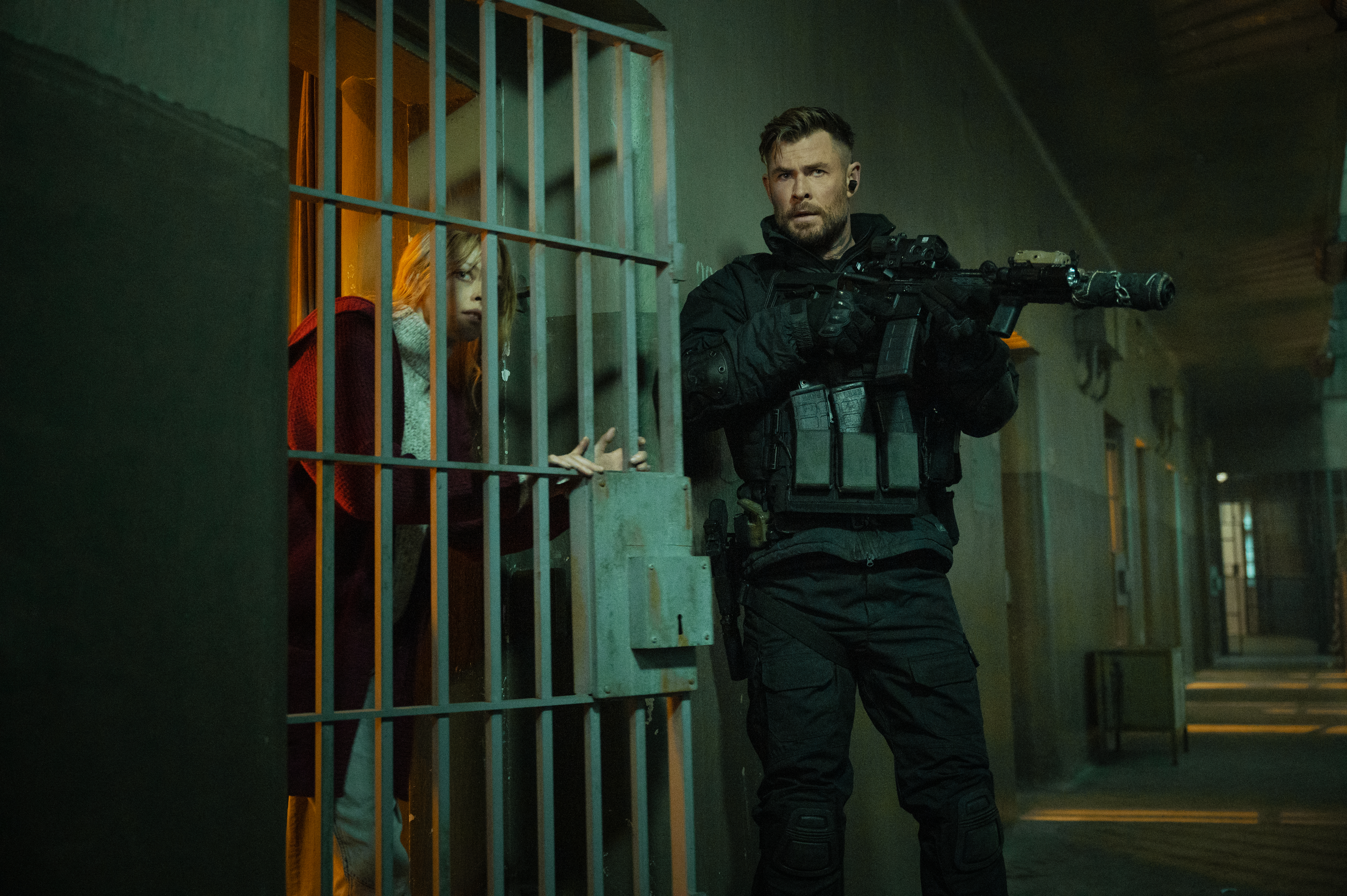 Chris Hemsworth holds an assault rifle outside of a jail cell holding Tinatin Dalakishvili in Extraction 2. Chris Hemsworth holds an assault rifle outside of a jail cell holding Tinatin Dalakishvili in Extraction 2.