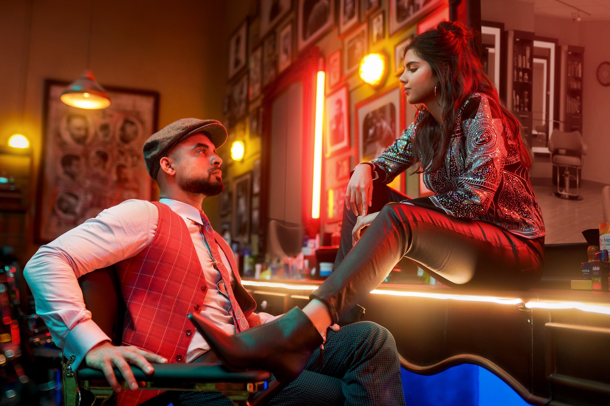 Tovino Thomas and Kalyani Priyadarshan face each other in a barber shop in Thallumaala. She sits on a counter, with her left leg on the right arm of the chair he sits in, while they look at each other. Tovino Thomas and Kalyani Priyadarshan face each other in a barber shop in Thallumaala. She sits on a counter, with her left leg on the right arm of the chair he sits in, while they look at each other.