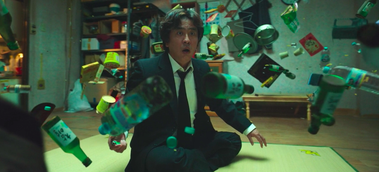 Random household objects float in front of a stunned-looking man, who is sitting cross-legged on the floor. Random household objects float in front of a stunned-looking man, who is sitting cross-legged on the floor.