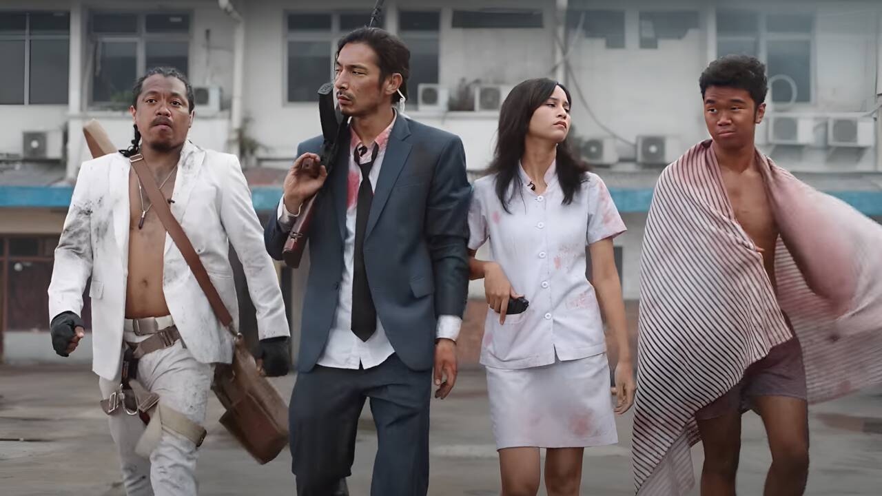 Four people, three men and one woman, walk alongside one another carrying weapons and looking disheveled. Four people, three men and one woman, walk alongside one another carrying weapons and looking disheveled.