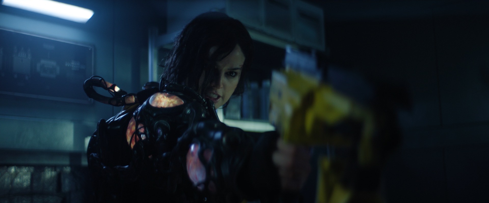 A woman (Eiza González) holding a yellow weapon while wearing a glowing bio-organic space suit in Ash. A woman (Eiza González) holding a yellow weapon while wearing a glowing bio-organic space suit in Ash.