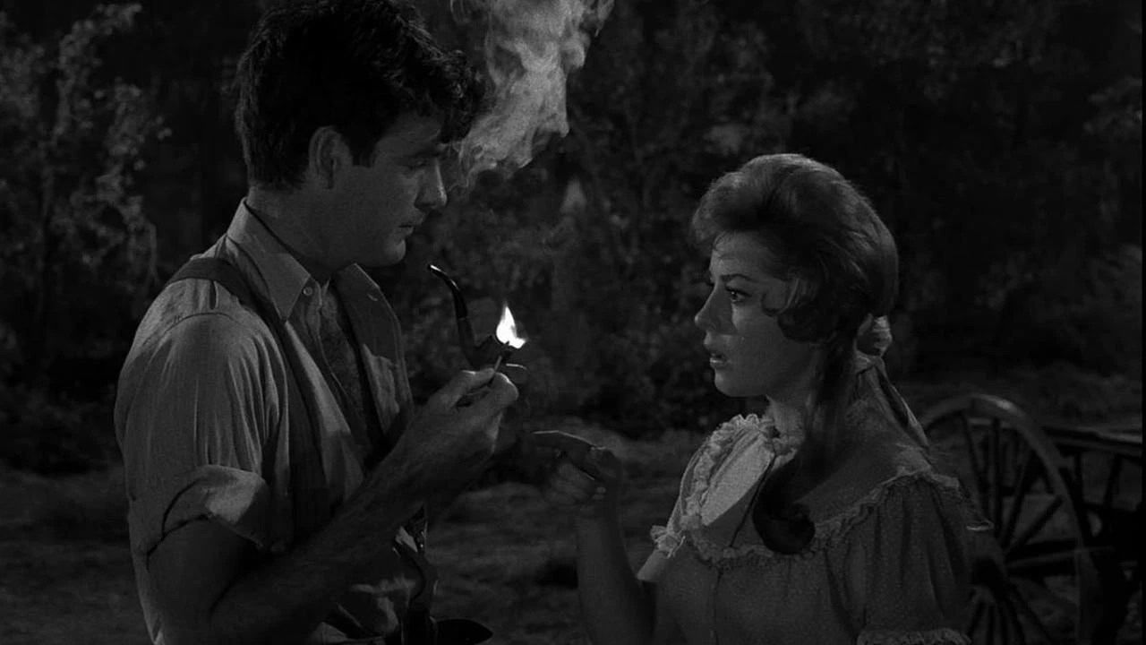 A woman staring in astonishment at a man lighting his pipe with a lit match in The Last Rites of Jeff Myrtlebank, an episode of The Twilight Zone. A woman staring in astonishment at a man lighting his pipe with a lit match in The Last Rites of Jeff Myrtlebank, an episode of The Twilight Zone.