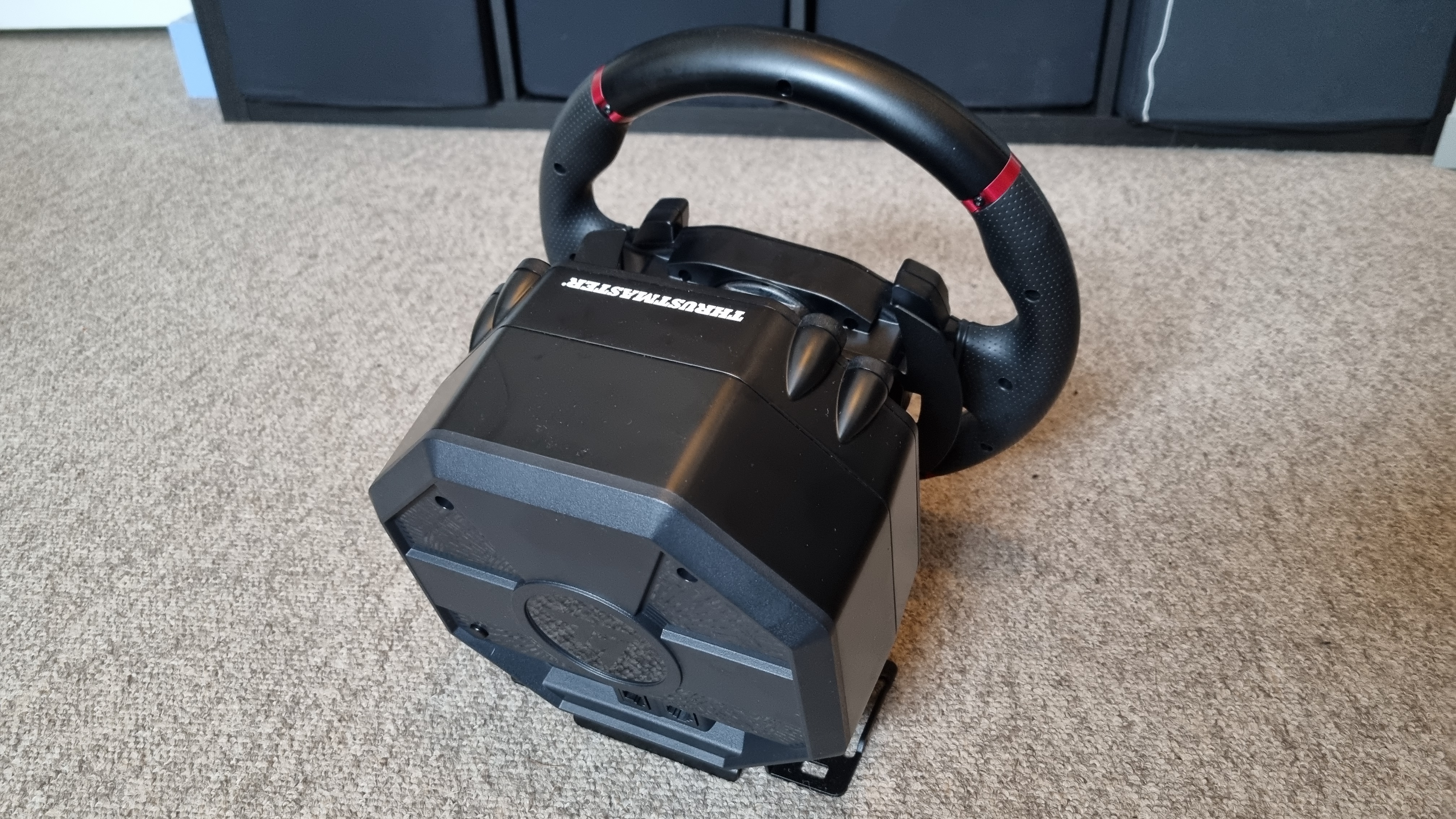 The Thrustmaster T598 wheel and pedal set, show from various angles on carpet