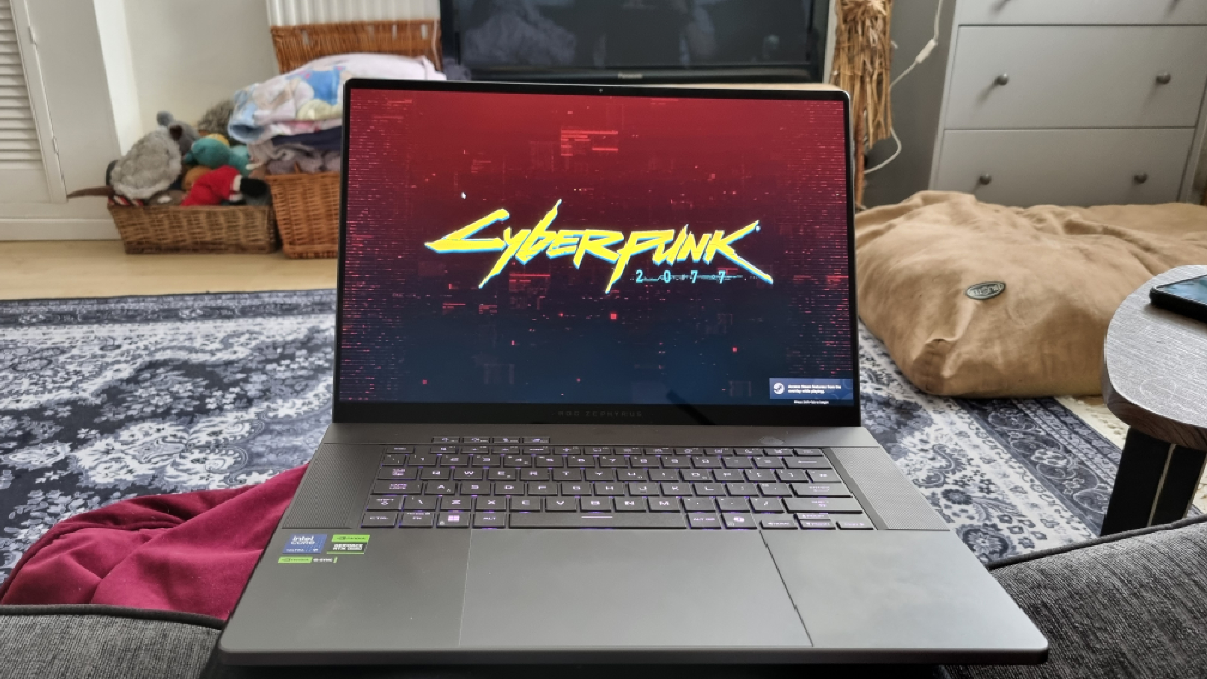 The Asus ROG Zephyrus G16 gaming laptop booting Cyberpunk 2077 in front of a TV