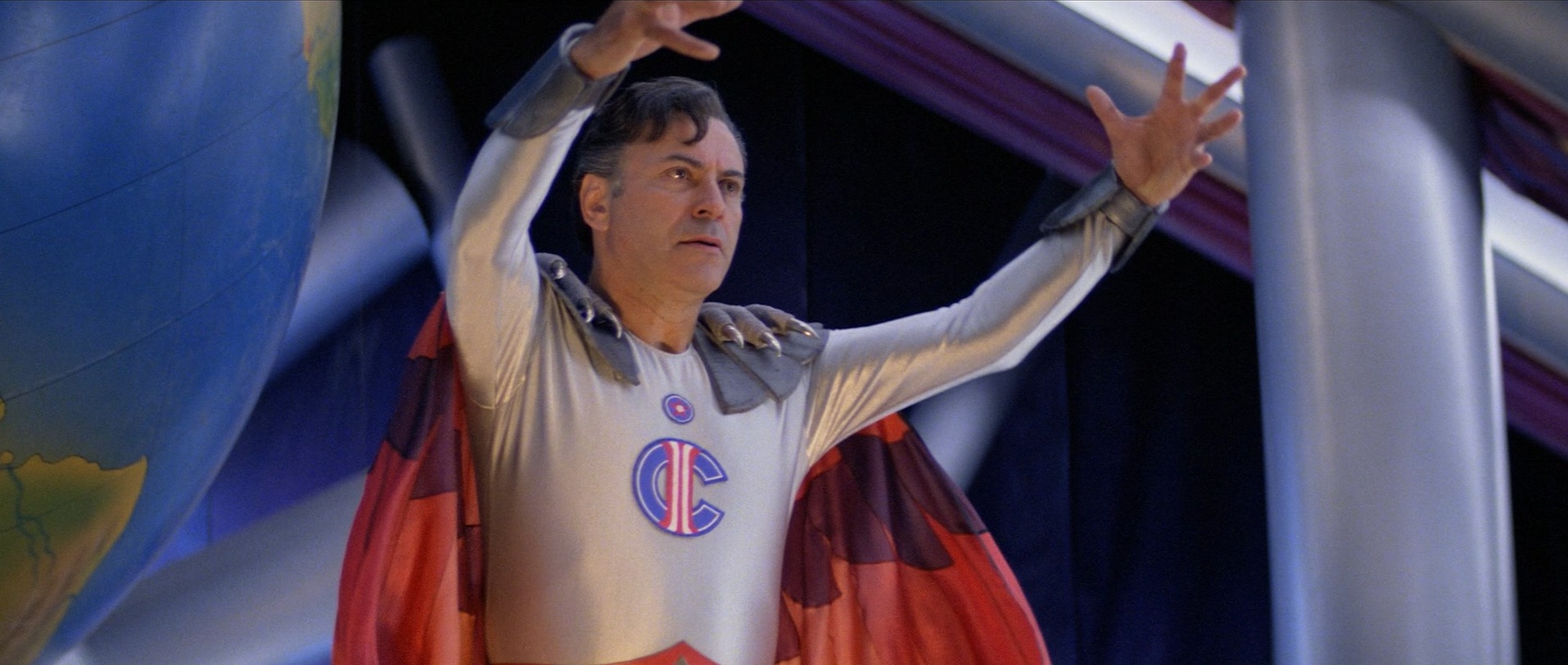 Alan Arkin wearing a goofy superhero costume with a logo that combines an I and a C in The Return of Captain Invincible. Alan Arkin wearing a goofy superhero costume with a logo that combines an I and a C in The Return of Captain Invincible.