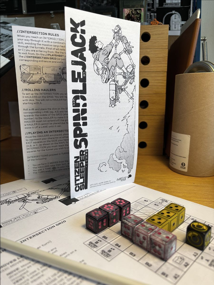 A photograph of the Citizen Sleeper board game pieces, which include a manual and ten six-sided dice A photograph of the Citizen Sleeper board game pieces, which include a manual and ten six-sided dice