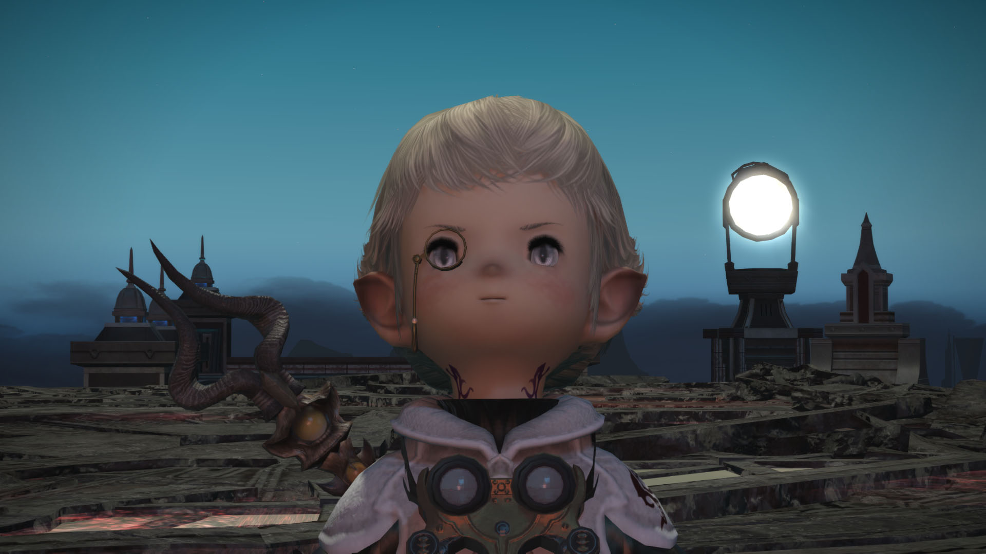 Papalymo, a small being with elf ears and a monocle, stands in front of a series of strange stone structures