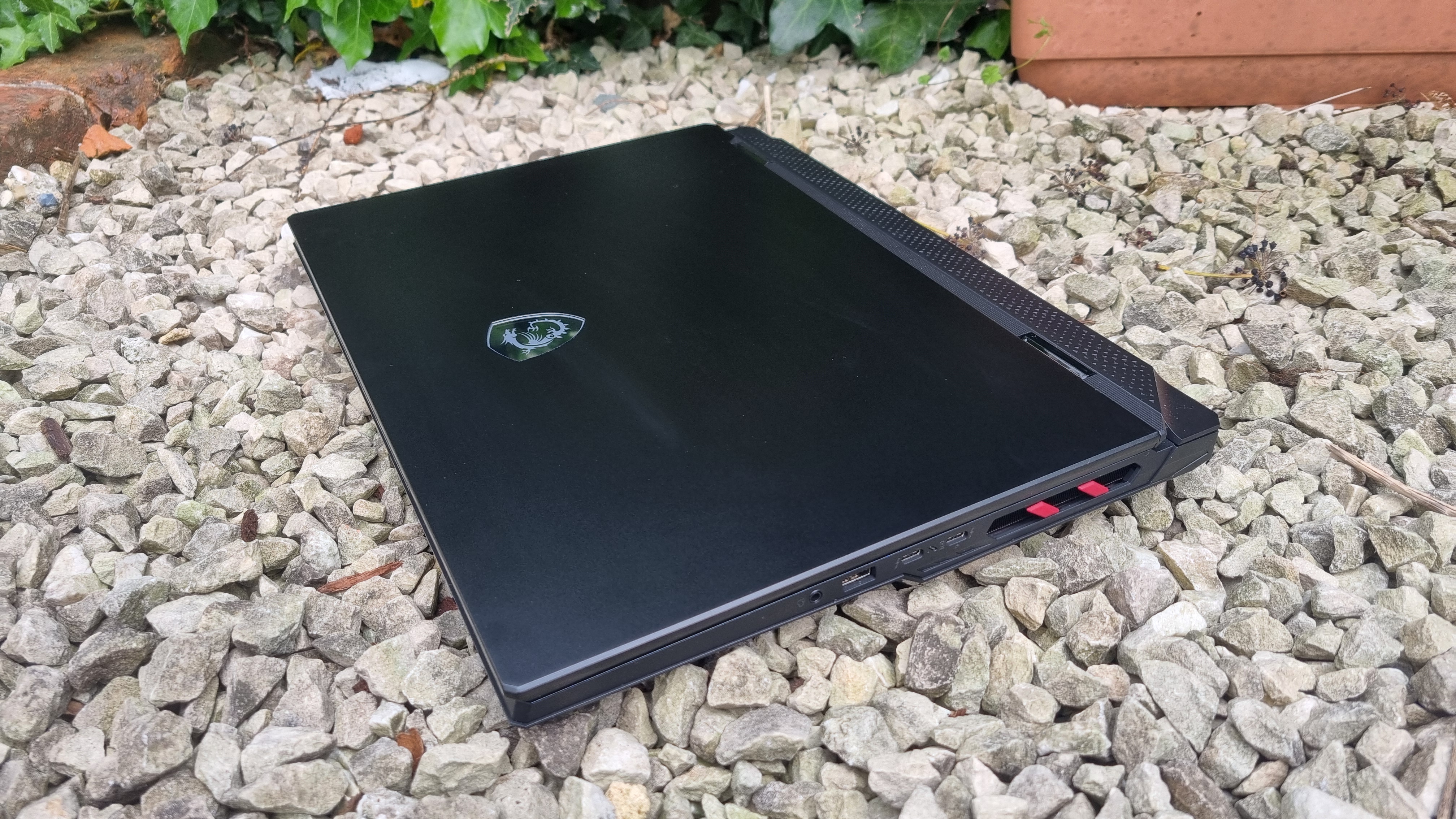 The MSI Raider 18 HX AI A2XW closed, at a 3/4 angle on white gravel