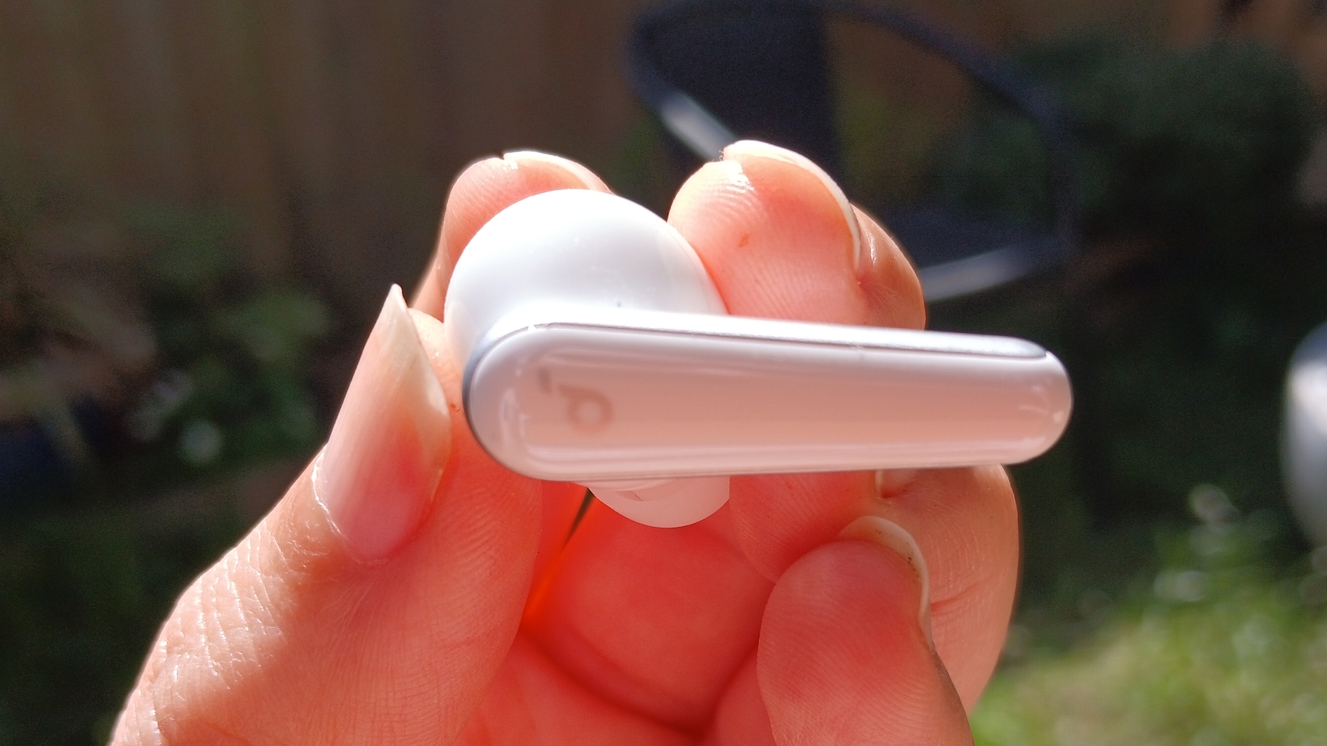 The Soundcore Liberty 5 earbuds outside in the sunlight and held by our reviewer, Katie Wickens.