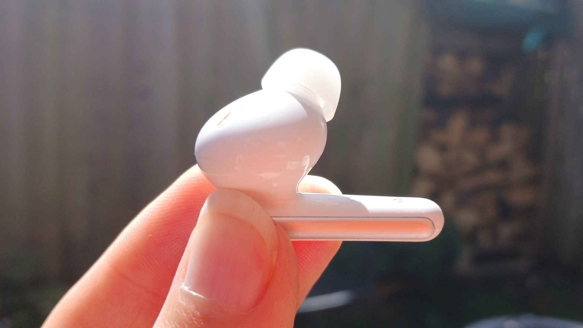 The Soundcore Liberty 5 earbuds outside in the sunlight and held by our reviewer, Katie Wickens.