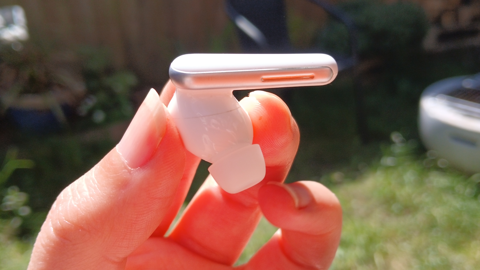 The Soundcore Liberty 5 earbuds outside in the sunlight and held by our reviewer, Katie Wickens.