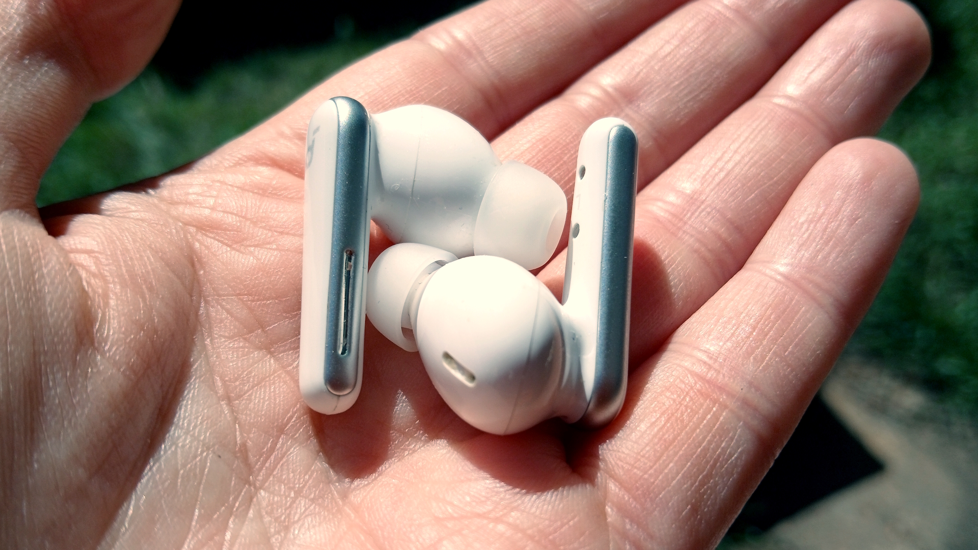 The Soundcore Liberty 5 earbuds outside in the sunlight and held by our reviewer, Katie Wickens.