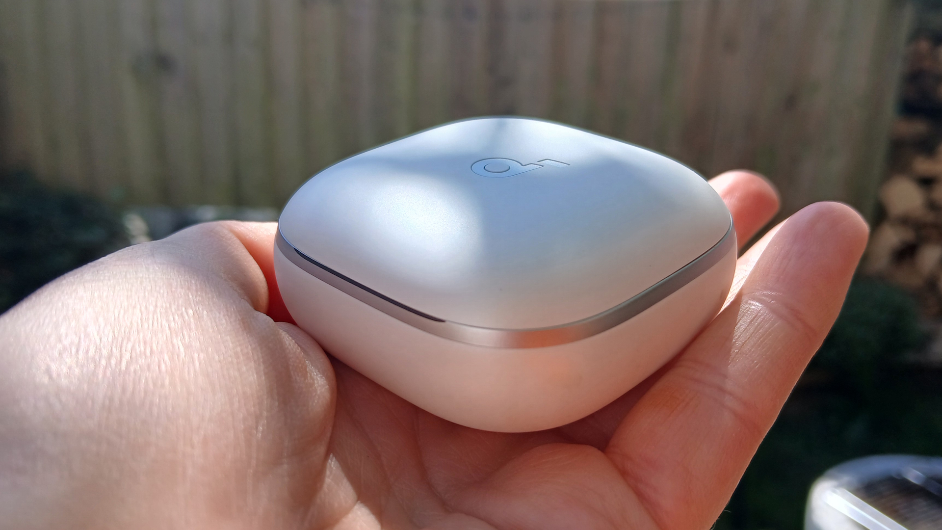 The Soundcore Liberty 5 earbuds outside in the sunlight and held by our reviewer, Katie Wickens.