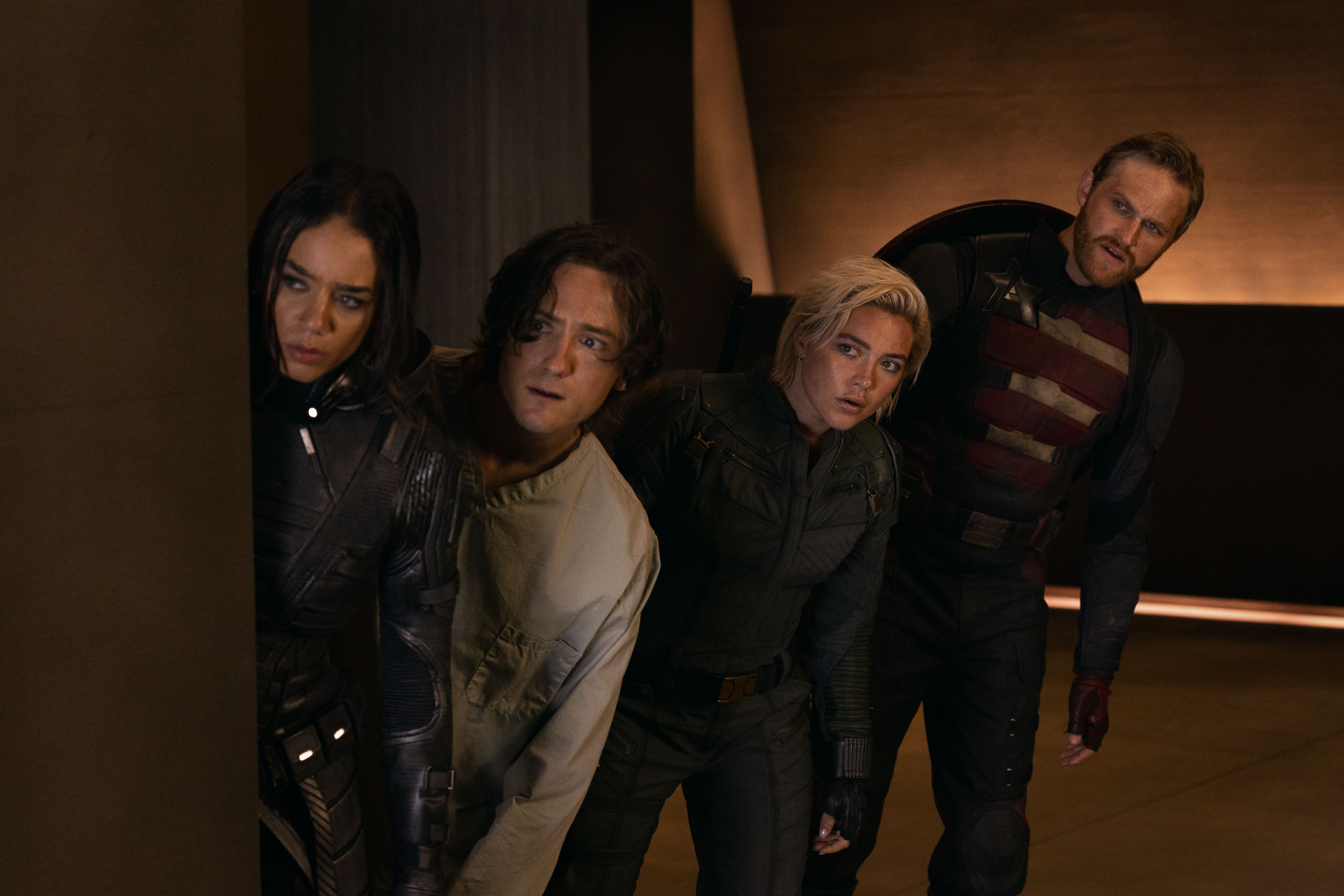 Hannah John-Kamen as Ghost, Lewis Pullman as Bob, Florence Pugh as Yelena, and Wyatt Russell as John Walker in Thunderbolts*, all leaning around a corner together while in their superhero costumes Hannah John-Kamen as Ghost, Lewis Pullman as Bob, Florence Pugh as Yelena, and Wyatt Russell as John Walker in Thunderbolts*, all leaning around a corner together while in their superhero costumes