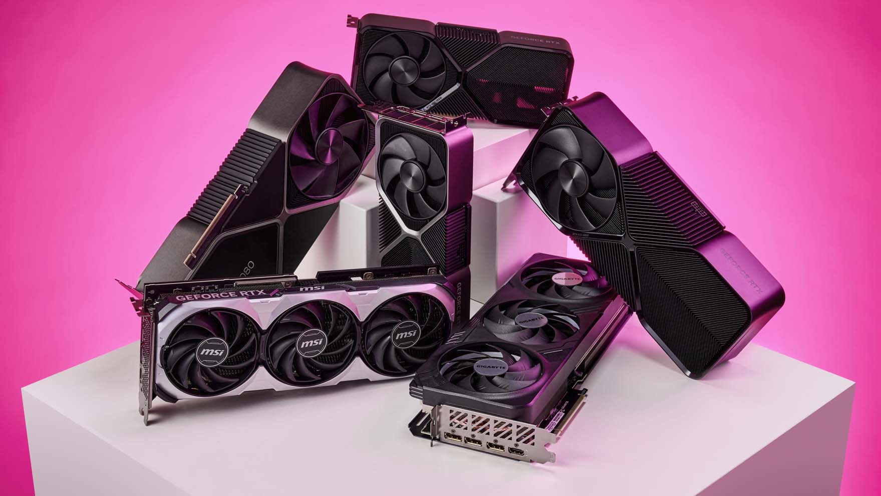 Various graphics cards set atop a white plinth on a pink gradient background