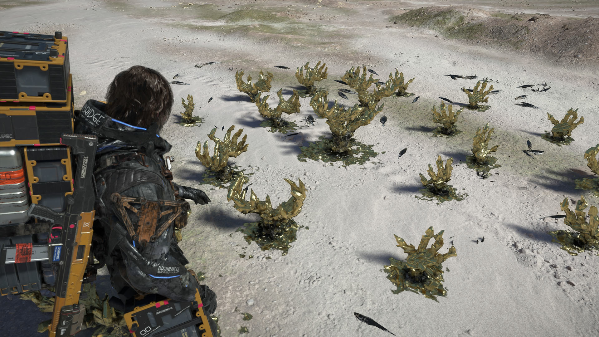 A Death Stranding 2 screenshot showing the character looking at golden crystals that look like claws. A Death Stranding 2 screenshot showing the character looking at golden crystals that look like claws.